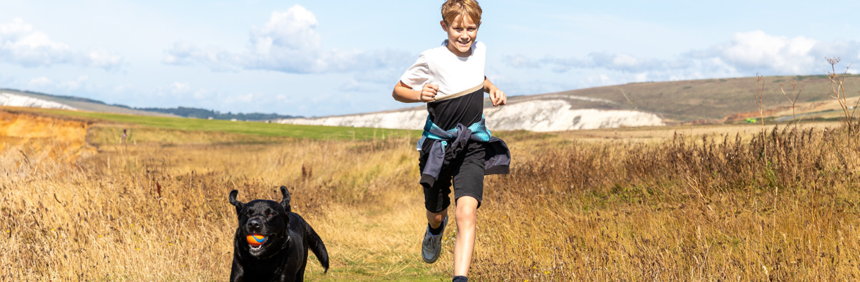 Boy and a dog running along the coast on the Isle of Wight